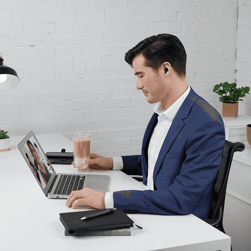 Homem trabalhando no computador enquanto usa o Phonak Virto para ligações em modo mãos livres